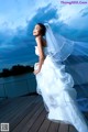 A woman in a wedding dress standing on a dock.