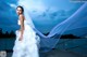 A woman in a wedding dress standing on a dock.