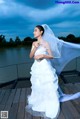 A woman in a wedding dress standing on a dock.