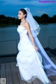 A woman in a wedding dress standing on a dock.