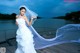 A woman in a wedding dress standing on a dock.