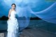 A woman in a wedding dress standing on a dock.