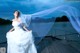 A woman in a wedding dress standing on a dock.