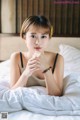 A woman laying on a bed with her hand on her chin.